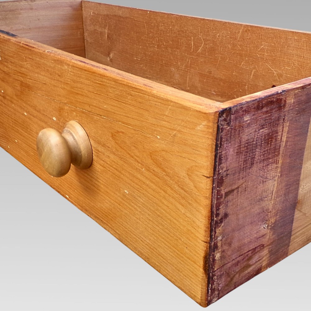 A nineteenth-century Victorian pine chest featuring three full-width drawers with turned wooden handles and keyholes, set on a plinth base. View VI