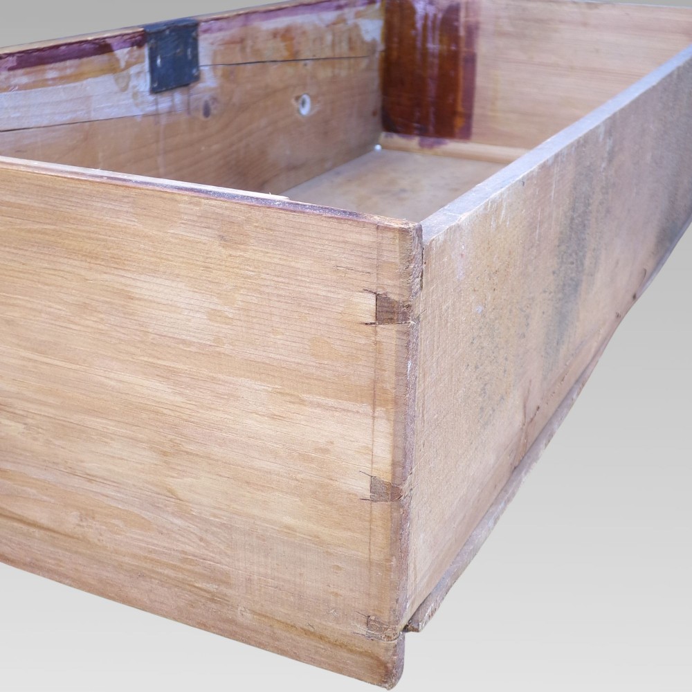 A nineteenth-century Victorian pine chest featuring three full-width drawers with turned wooden handles and keyholes, set on a plinth base. View VII