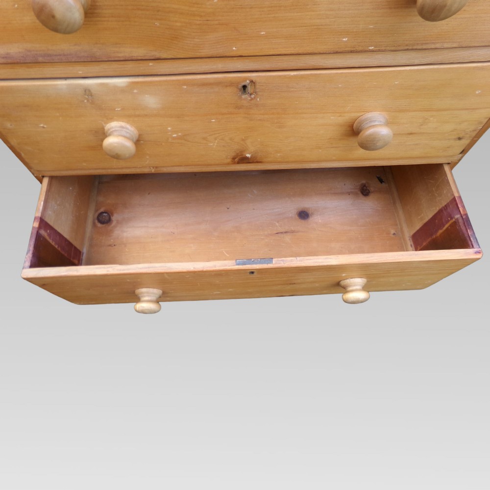 A nineteenth-century Victorian pine chest featuring three full-width drawers with turned wooden handles and keyholes, set on a plinth base. View VIII