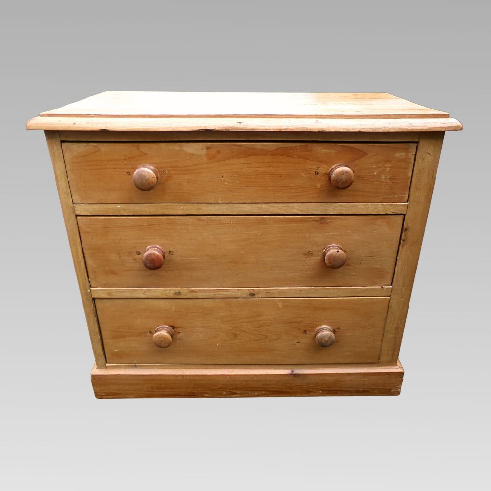 A nineteenth-century Victorian pine chest of drawers featuring three full-width drawers with turned wooden knob handles and a flat plinth base.
