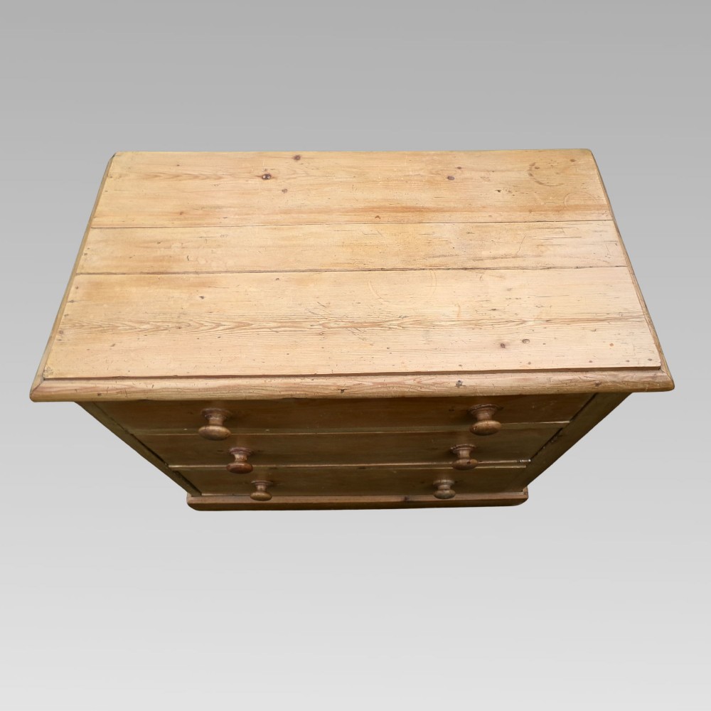 A nineteenth-century Victorian pine chest of drawers featuring three full-width drawers with turned wooden knob handles and a flat plinth base. View II