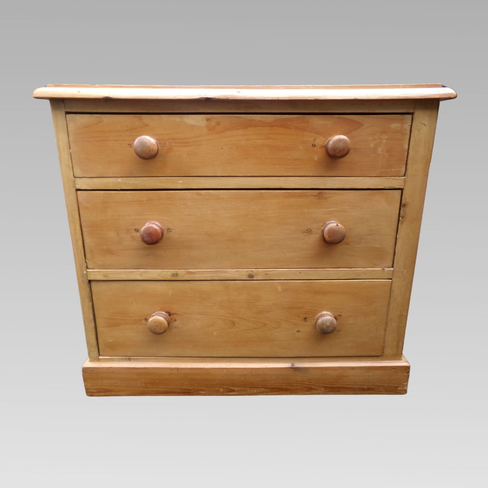 A nineteenth-century Victorian pine chest of drawers featuring three full-width drawers with turned wooden knob handles and a flat plinth base. View IV