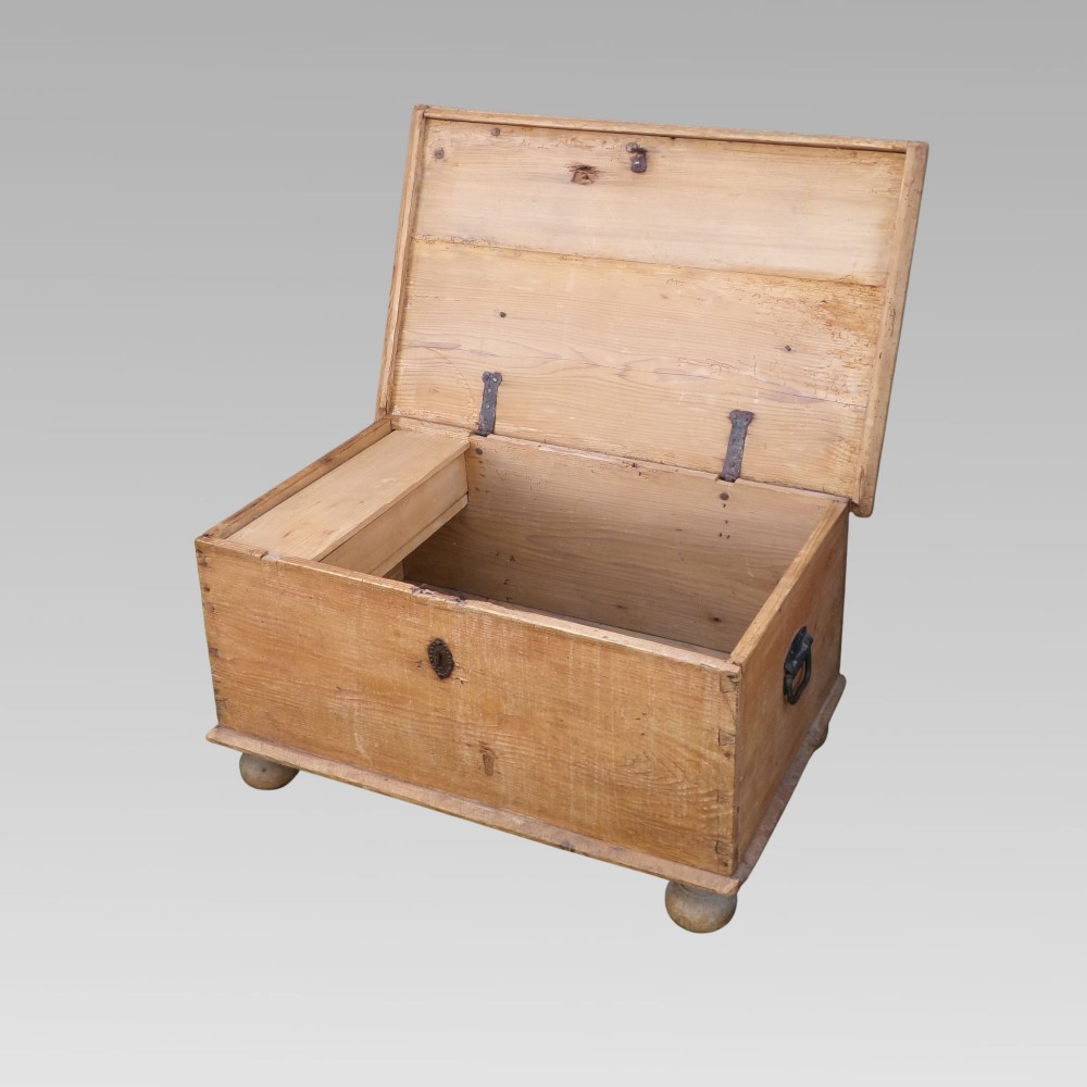 A rectangular nineteenth-century pine blanket box with turned bun feet, side iron drop handles, and a central keyhole escutcheon. View II