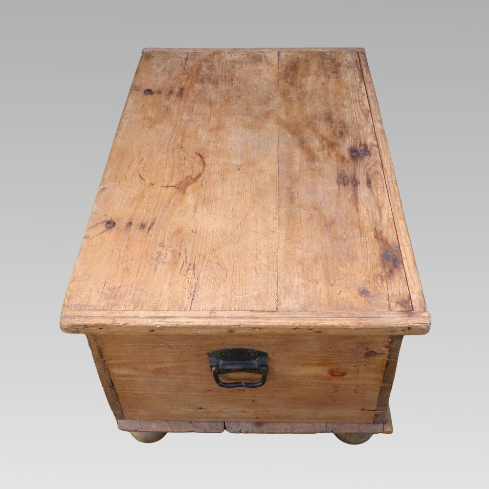 A rectangular nineteenth-century pine blanket box with turned bun feet, side iron drop handles, and a central keyhole escutcheon. View V