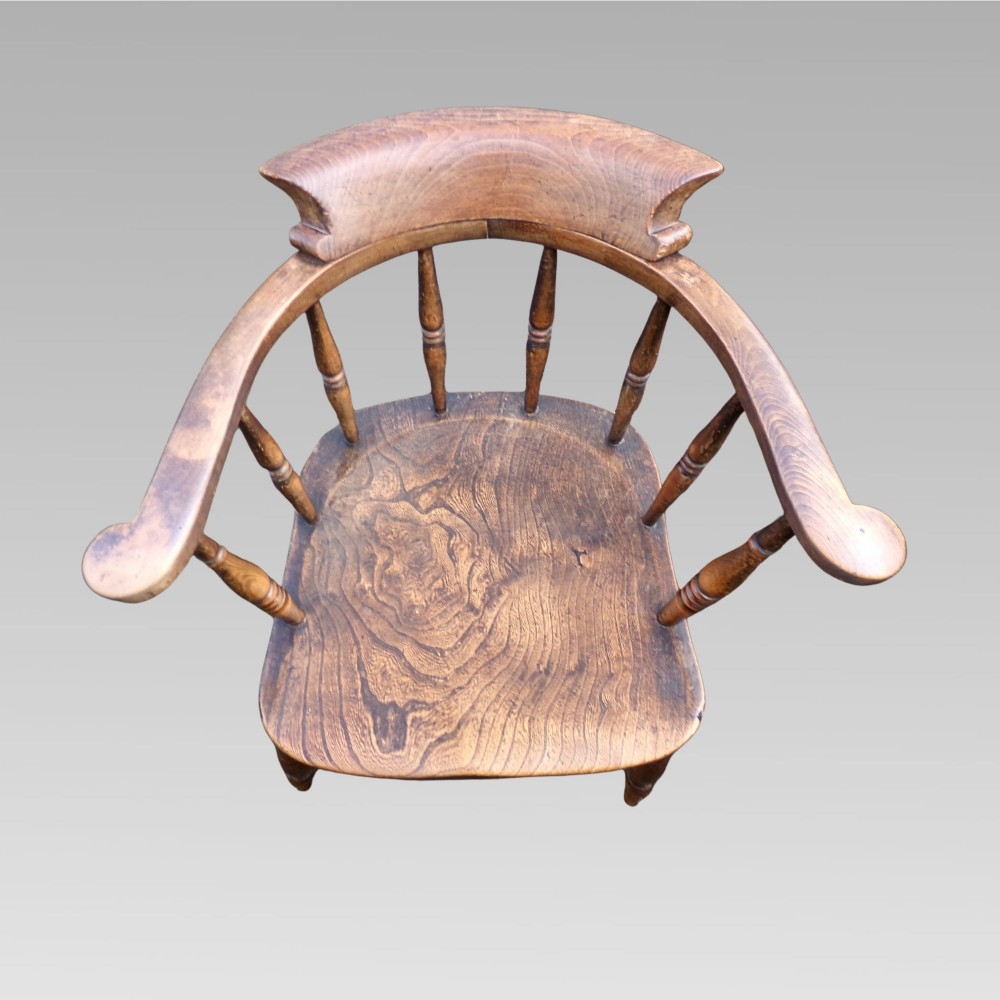 A nineteenth-century elm and beech smokers bow captains armchair featuring turned legs, vertical spindles, and a shaped seat. View II
