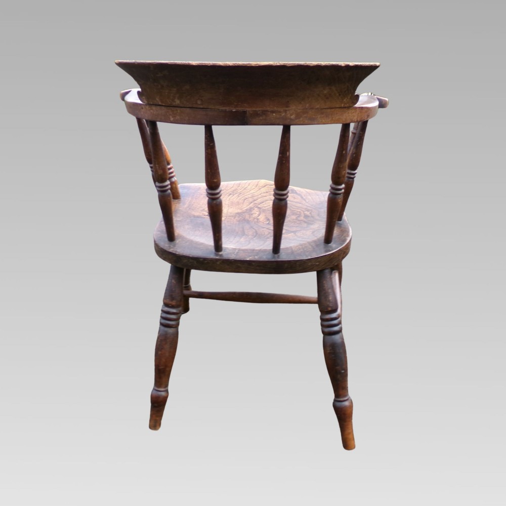 A nineteenth-century elm and beech smokers bow captains armchair featuring turned legs, vertical spindles, and a shaped seat. View VI