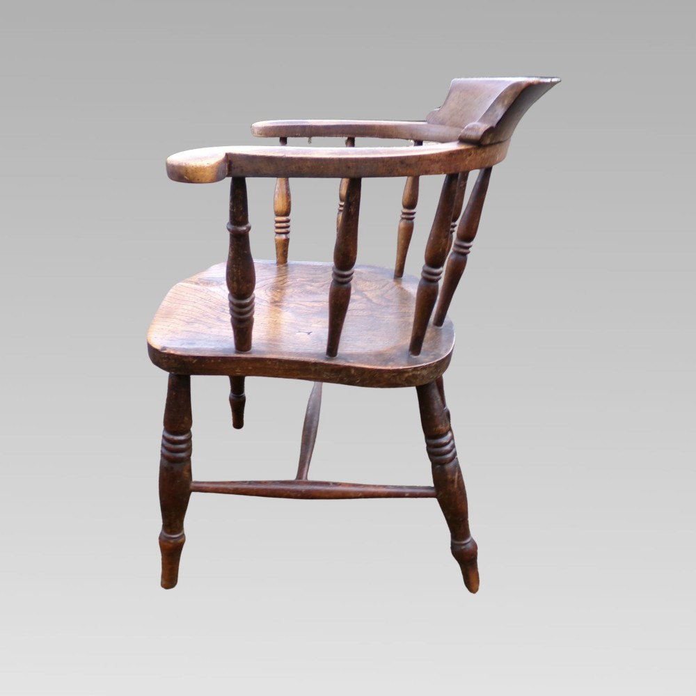 A nineteenth-century elm and beech smokers bow captains armchair featuring turned legs, vertical spindles, and a shaped seat. View VII