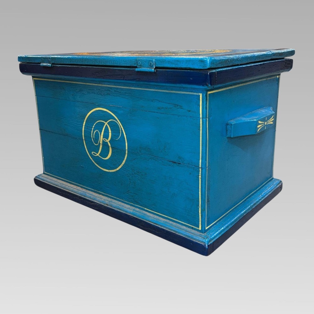 A blue painted wooden storage box featuring a hand-painted scene of sailing yachts and lettering reading The Yacht Britannia Cowes I.O.W. 1902. View III