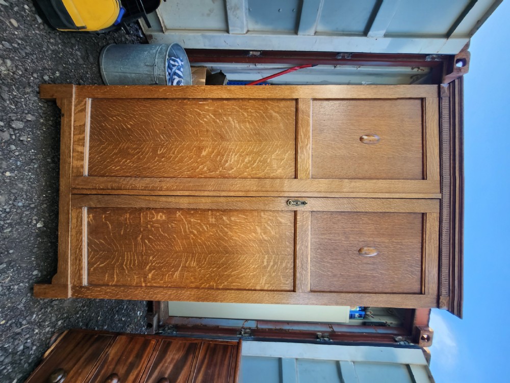 A tall 1920s limed oak gentlemans wardrobe featuring twin panelled doors with oval carved handles and a fluted top cornice. View II