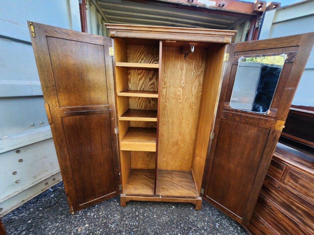 A tall 1920s limed oak gentlemans wardrobe featuring twin panelled doors with oval carved handles and a fluted top cornice. View IV