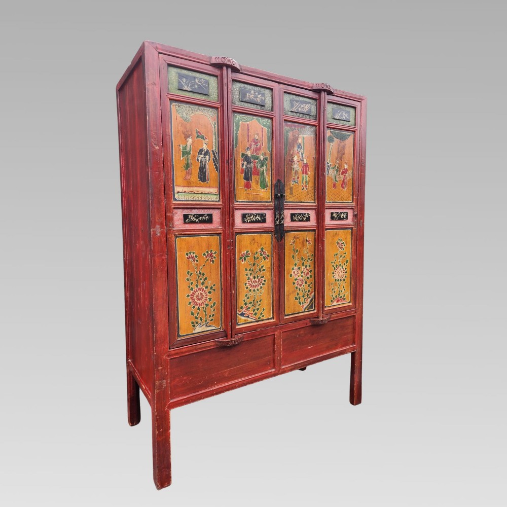 A tall red lacquered Chinese cabinet featuring four vertical doors decorated with hand-painted figurative scenes and floral motifs.