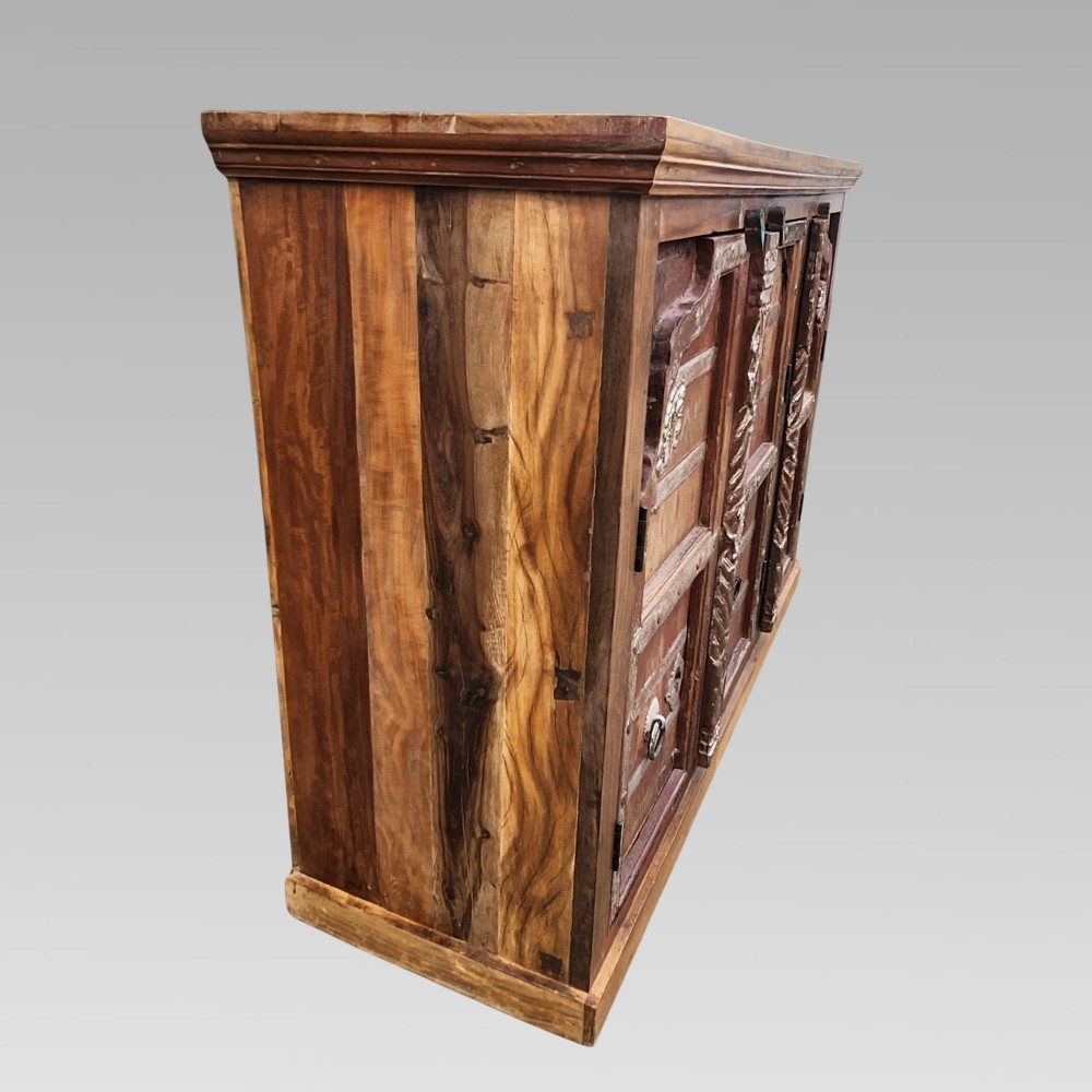 A rustic three-door reclaimed teak sideboard featuring hand-carved floral pilasters, iron ring handles, and metal stud accents. View IV