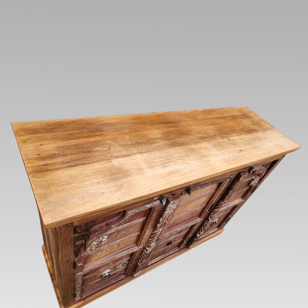 A rustic three-door reclaimed teak sideboard featuring hand-carved floral pilasters, iron ring handles, and metal stud accents. View V