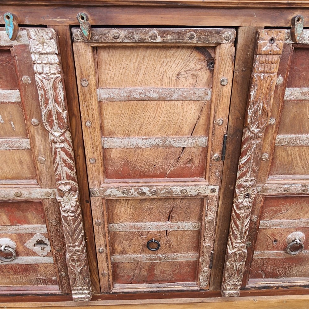 A rustic three-door reclaimed teak sideboard featuring hand-carved floral pilasters, iron ring handles, and metal stud accents. View VII