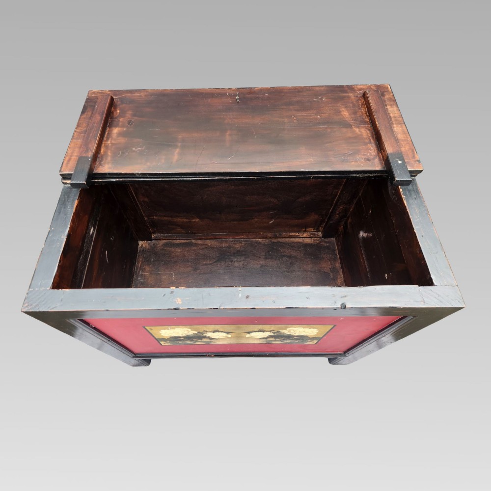 A dark lacquered wooden storage chest featuring a framed red panel with a hand-painted floral image of white peonies on a gold background. View III