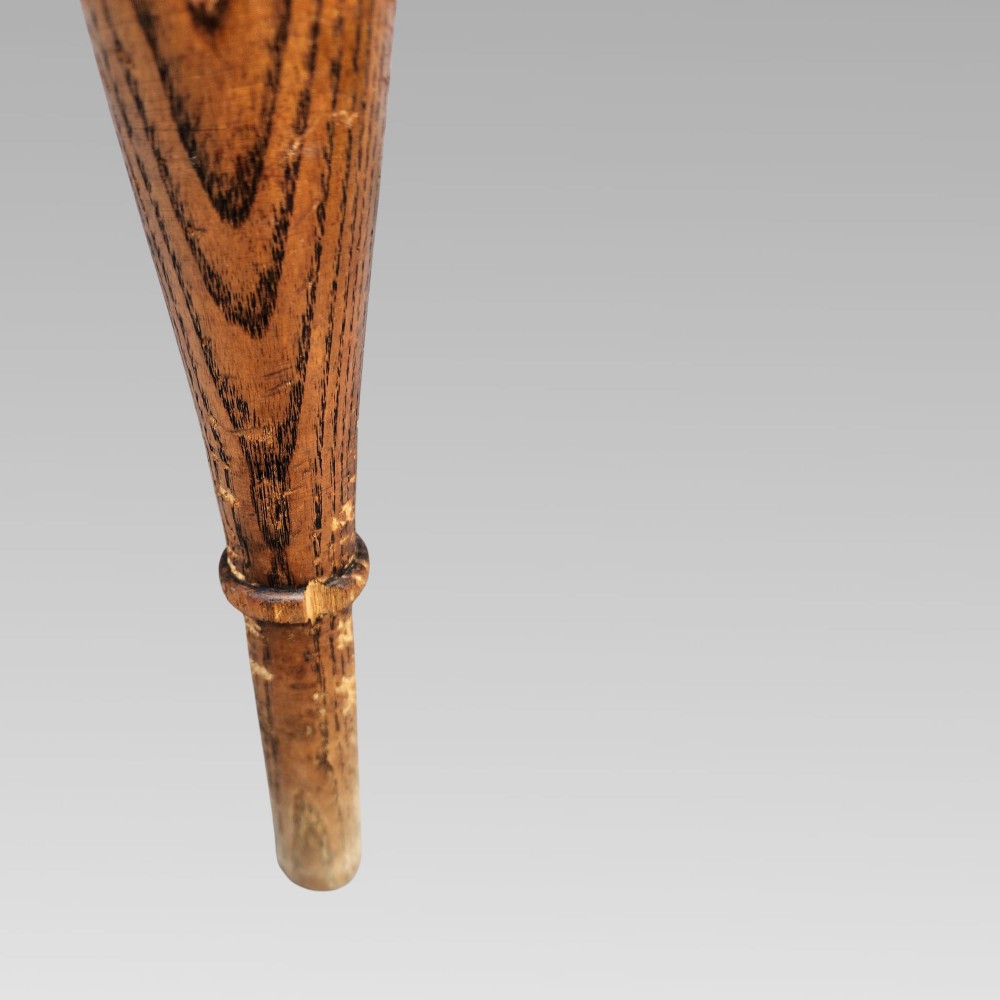An antique elm Windsor armchair featuring a hoop back, a pierced splat, turned legs, and a curved crinoline stretcher. View VII