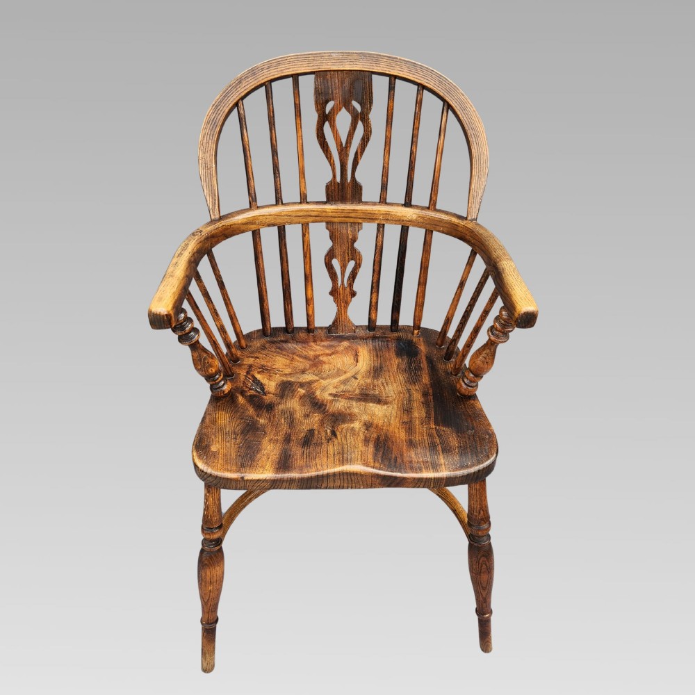 An antique English Windsor armchair featuring a hoop spindle back, central pierced splat, shaped elm saddle seat, turned legs, and a steam-bent crinoline stretcher. View II