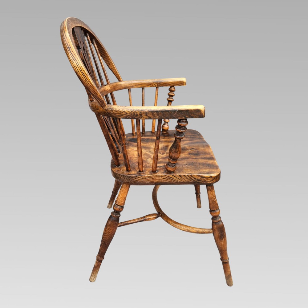 An antique English Windsor armchair featuring a hoop spindle back, central pierced splat, shaped elm saddle seat, turned legs, and a steam-bent crinoline stretcher. View III