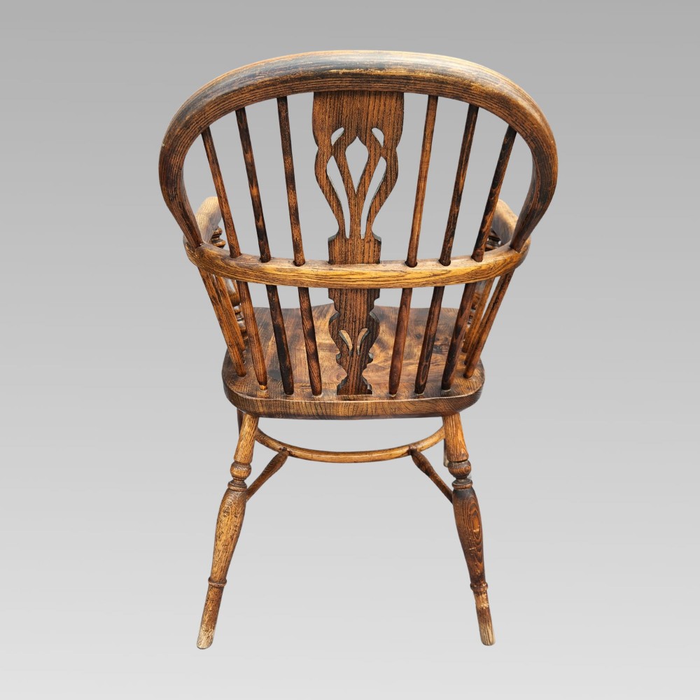 An antique English Windsor armchair featuring a hoop spindle back, central pierced splat, shaped elm saddle seat, turned legs, and a steam-bent crinoline stretcher. View IV