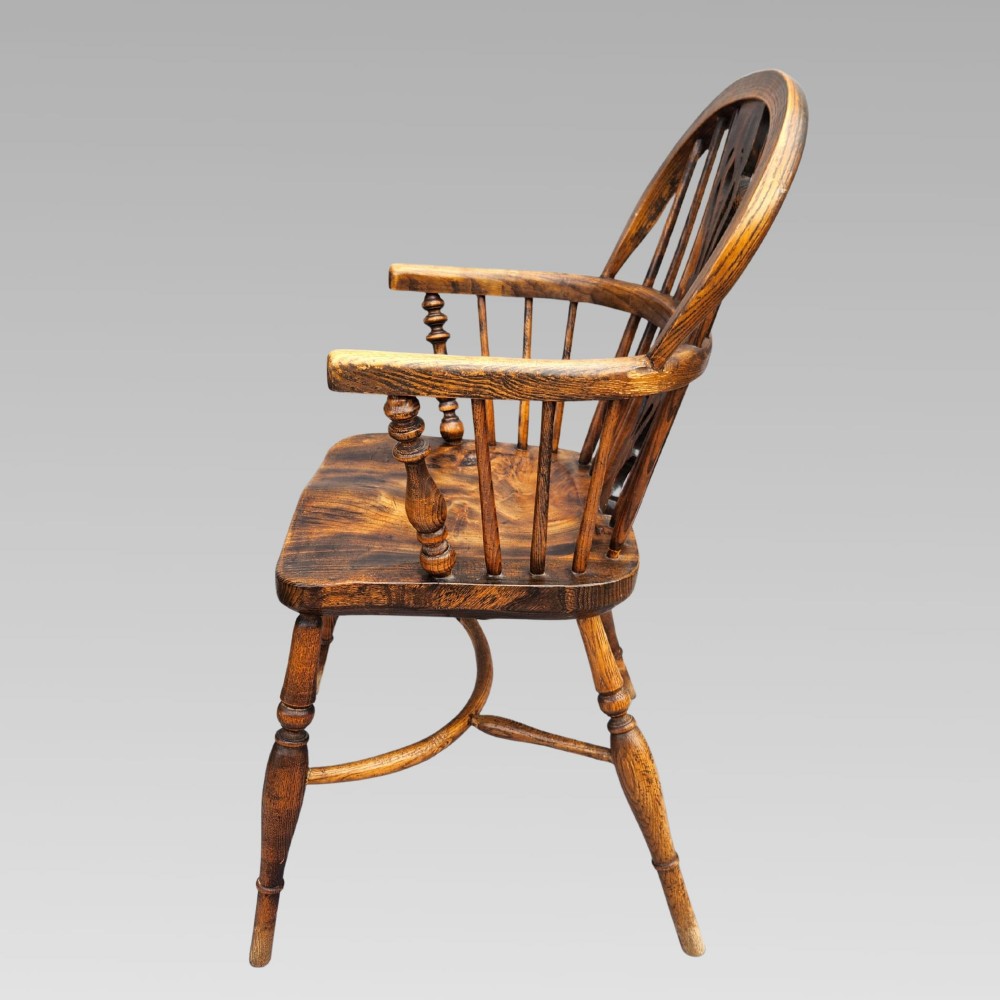 An antique English Windsor armchair featuring a hoop spindle back, central pierced splat, shaped elm saddle seat, turned legs, and a steam-bent crinoline stretcher. View V