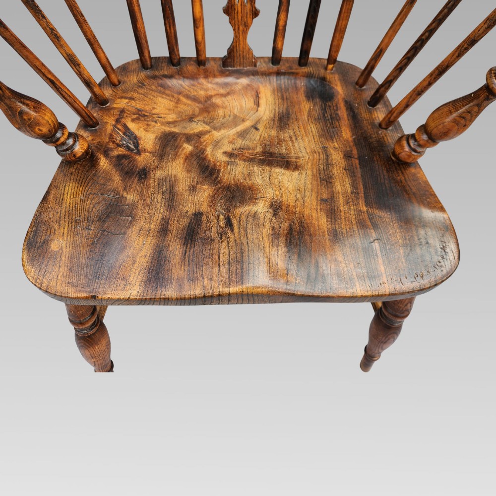 An antique English Windsor armchair featuring a hoop spindle back, central pierced splat, shaped elm saddle seat, turned legs, and a steam-bent crinoline stretcher. View VI