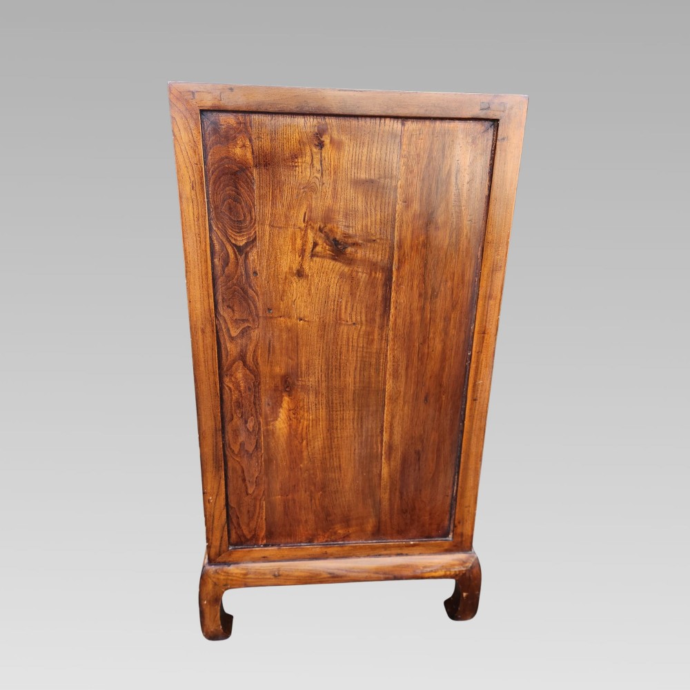A tall warm brown elm apothecary chest featuring sixteen small labelled drawers above two wider base drawers with metal ring pulls. View V