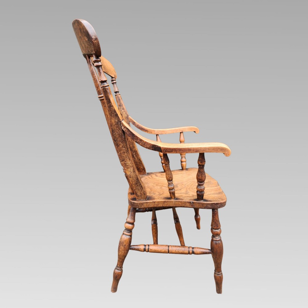 Victorian elm Windsor armchair featuring a central lyre-shaped splat, turned spindles, a curved crest rail, contoured solid seat, and turned wooden legs with stretchers. View III