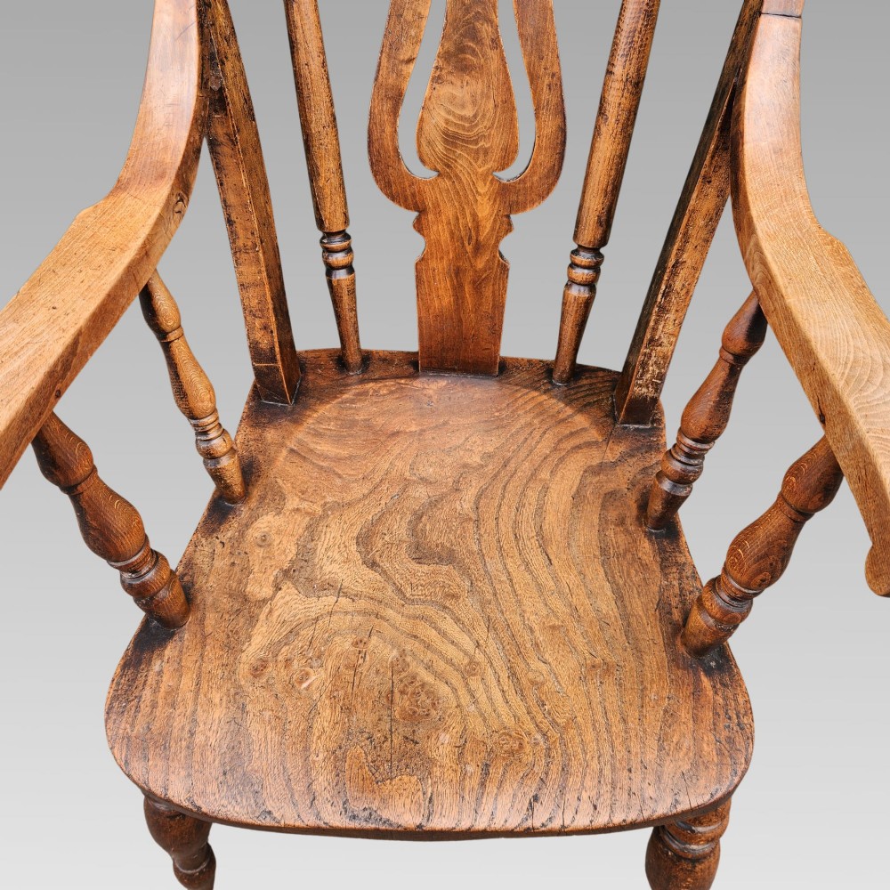 Victorian elm Windsor armchair featuring a central lyre-shaped splat, turned spindles, a curved crest rail, contoured solid seat, and turned wooden legs with stretchers. View IV
