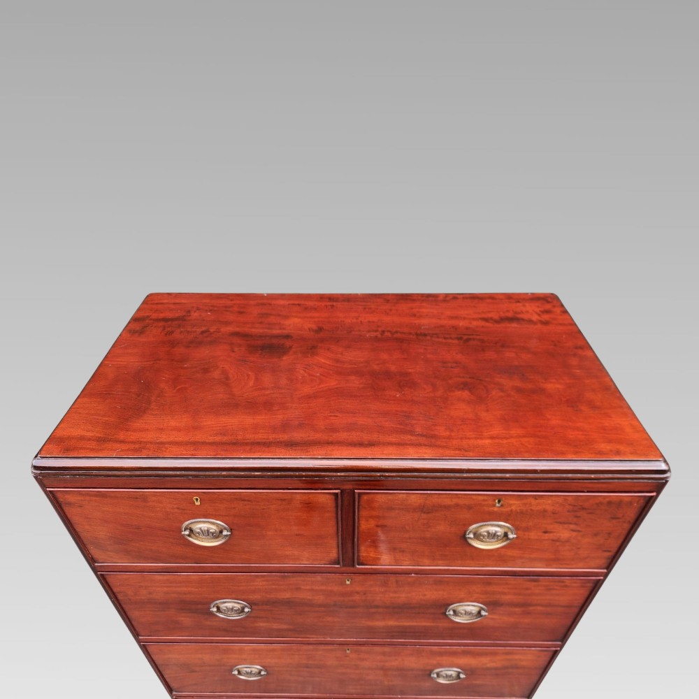 A Victorian flame mahogany chest of drawers featuring two short over three long drawers with oval brass handles. View IV