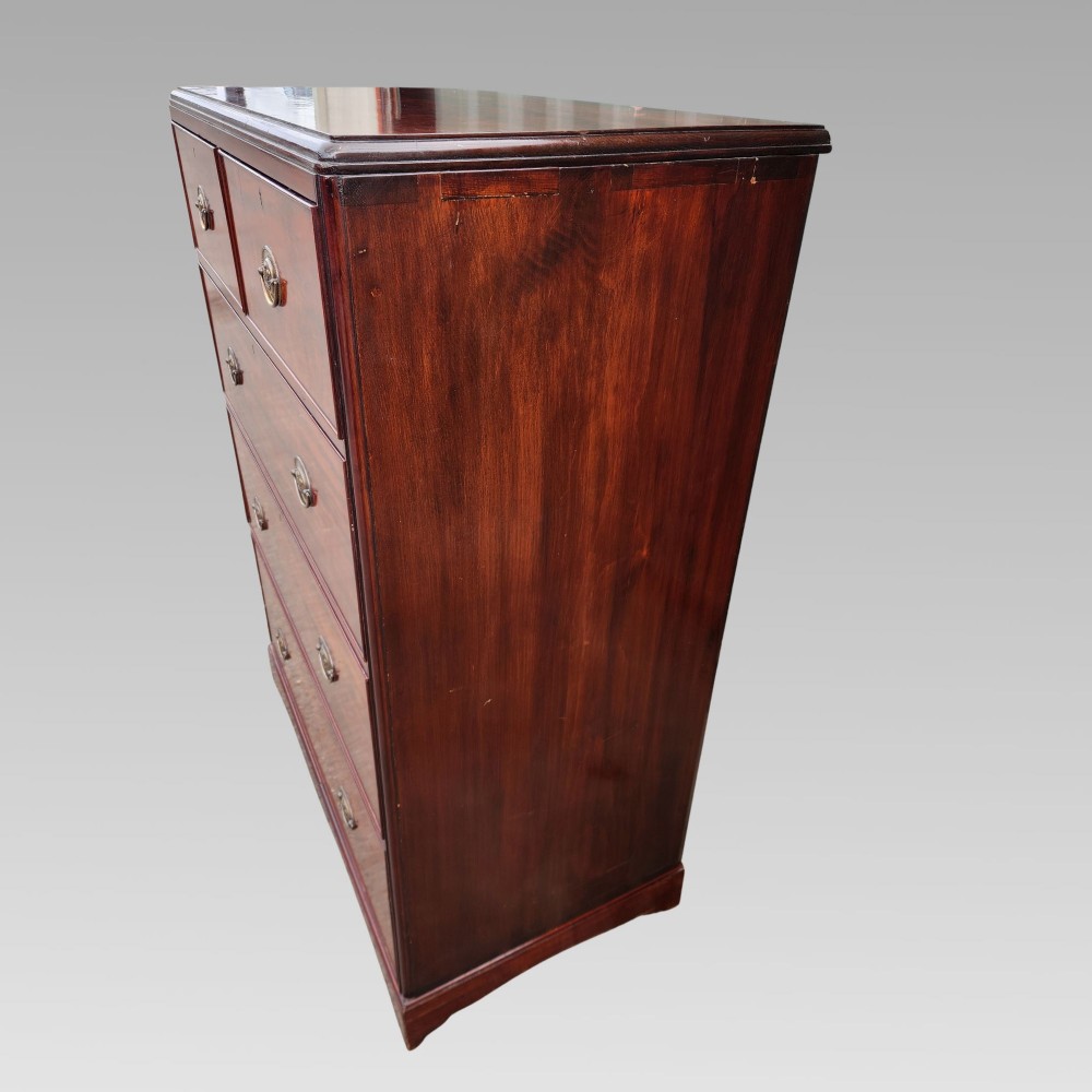 A Victorian flame mahogany chest of drawers featuring two short over three long drawers with oval brass handles. View VI