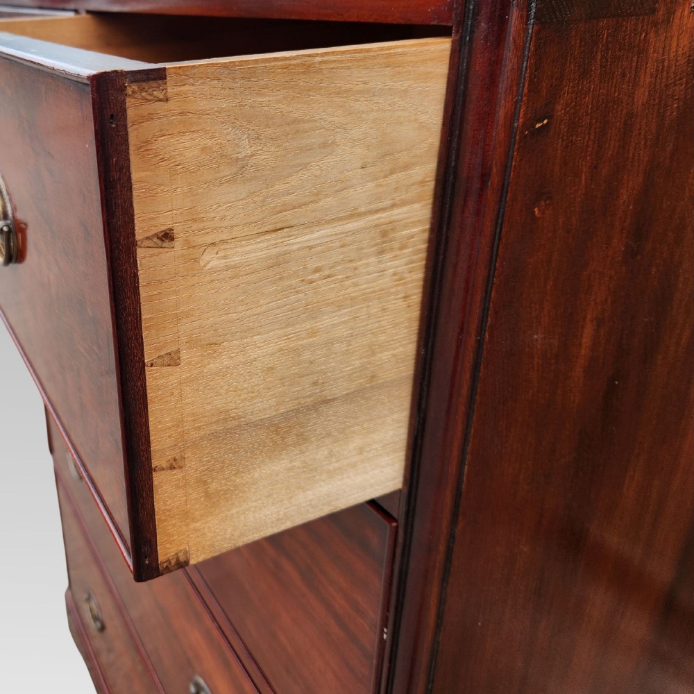 A Victorian flame mahogany chest of drawers featuring two short over three long drawers with oval brass handles. View VII