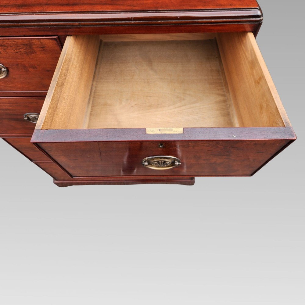 A Victorian flame mahogany chest of drawers featuring two short over three long drawers with oval brass handles. View IX