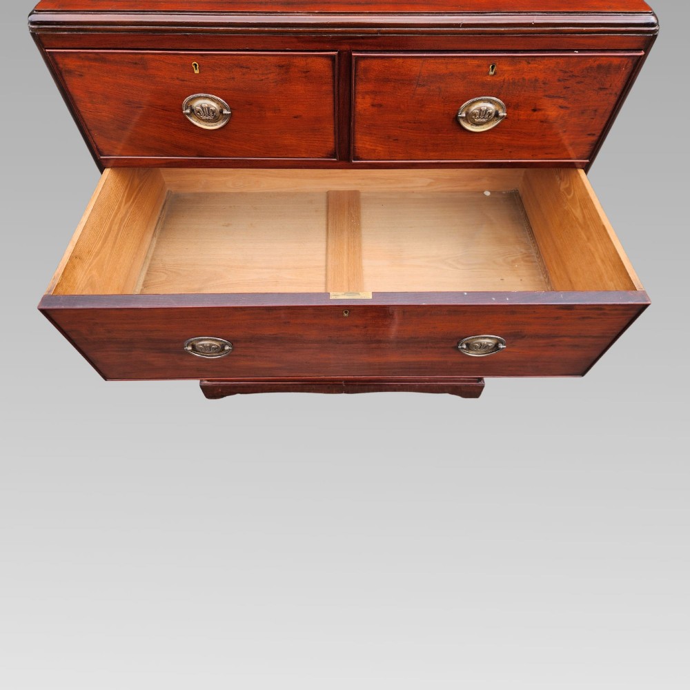 A Victorian flame mahogany chest of drawers featuring two short over three long drawers with oval brass handles. View X