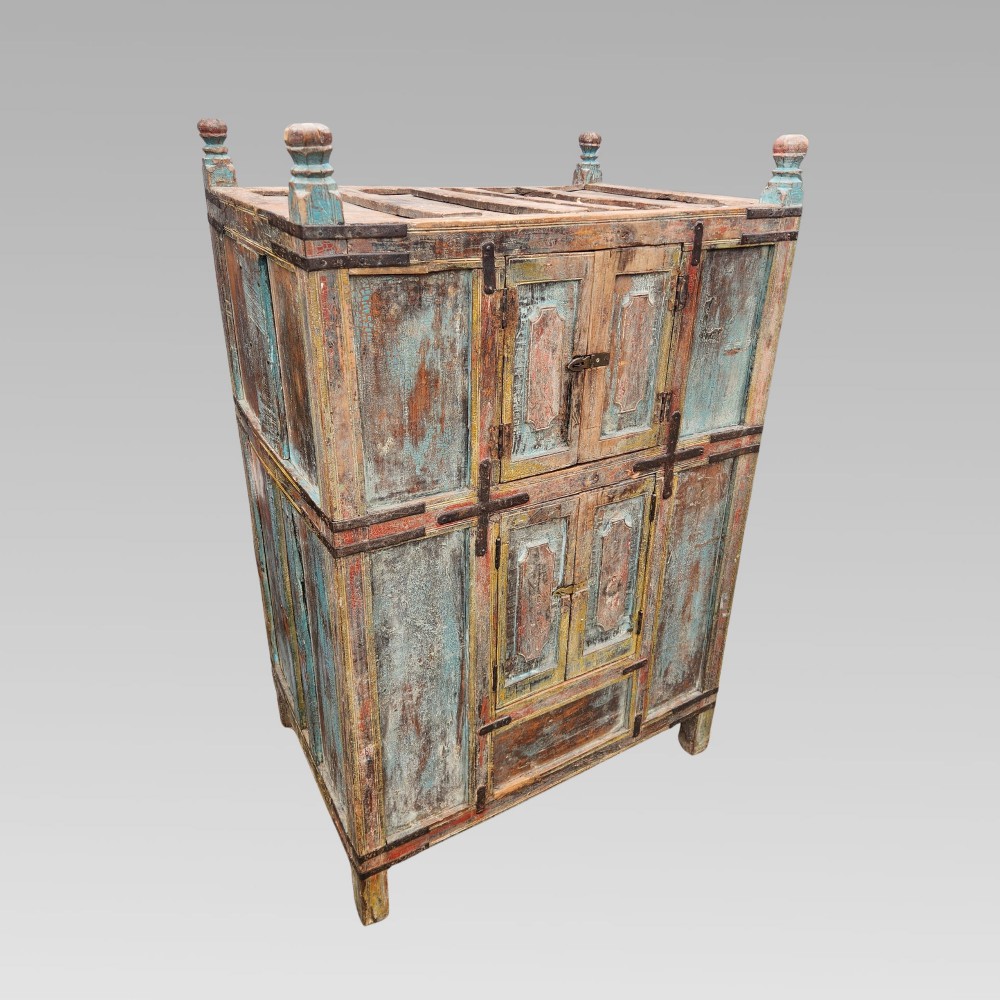 A tall antique Indian wooden almirah cabinet featuring layered distressed blue paint, iron strapping, panelled doors, and corner finials. View III