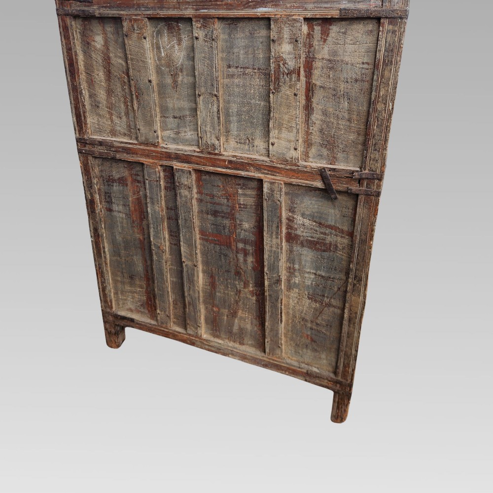 A tall antique Indian wooden almirah cabinet featuring layered distressed blue paint, iron strapping, panelled doors, and corner finials. View XII