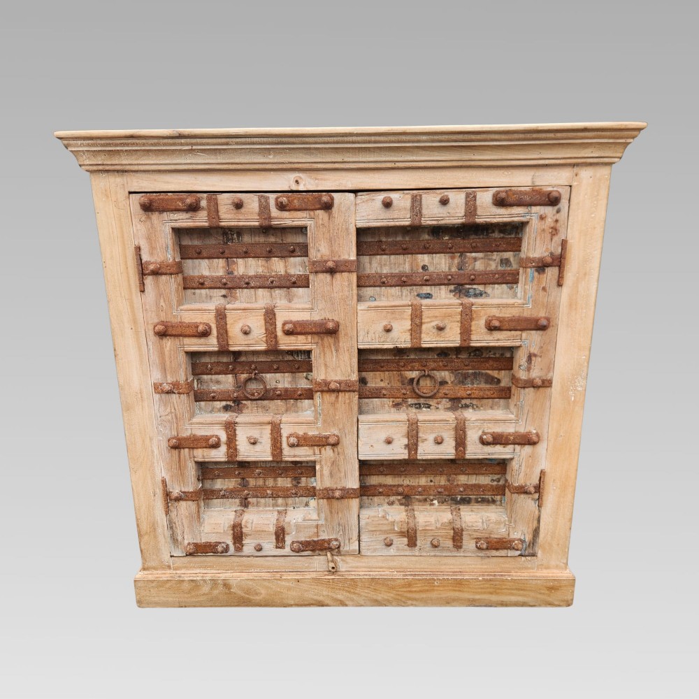 A light natural teak two-door storage cupboard featuring heavy iron straps, studs, and ring handles. View II