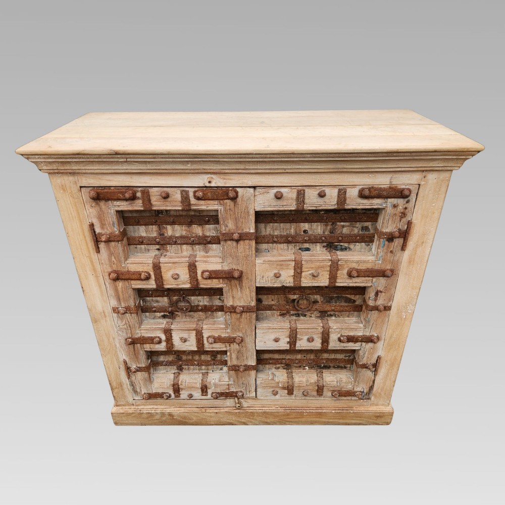 A light natural teak two-door storage cupboard featuring heavy iron straps, studs, and ring handles. View III