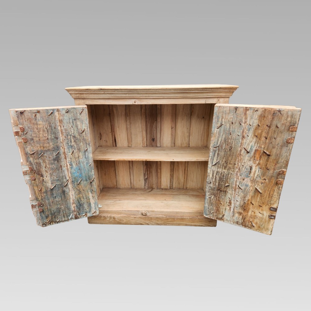 A light natural teak two-door storage cupboard featuring heavy iron straps, studs, and ring handles. View IV