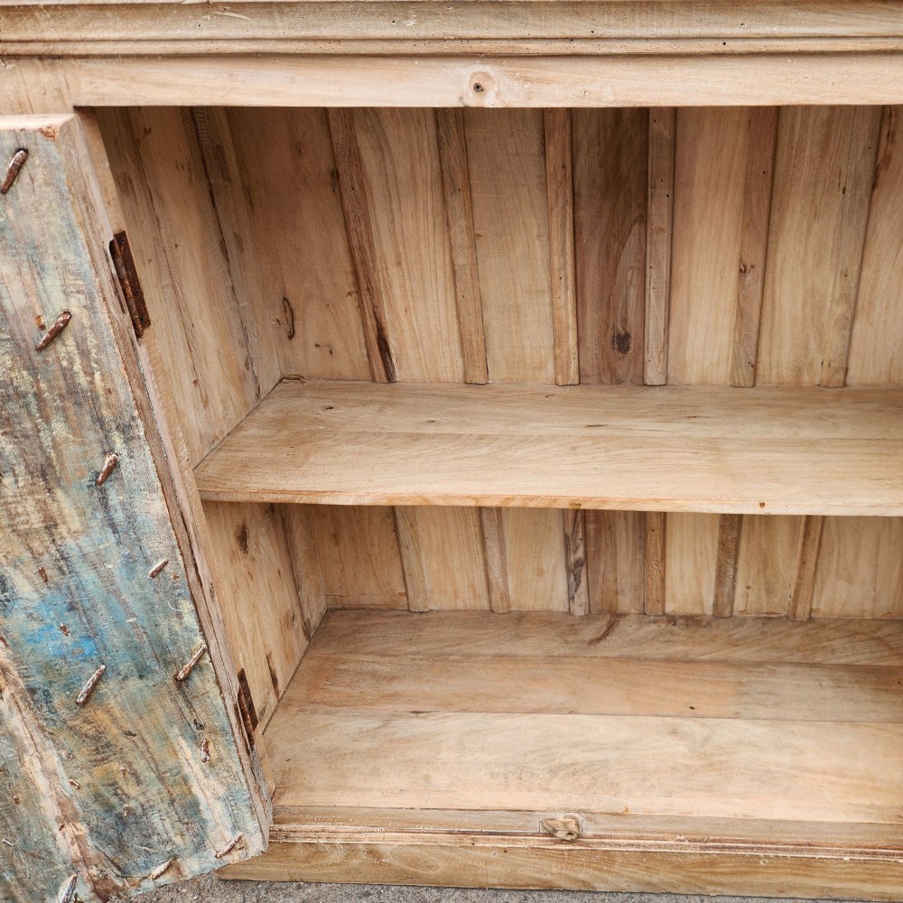 A light natural teak two-door storage cupboard featuring heavy iron straps, studs, and ring handles. View V