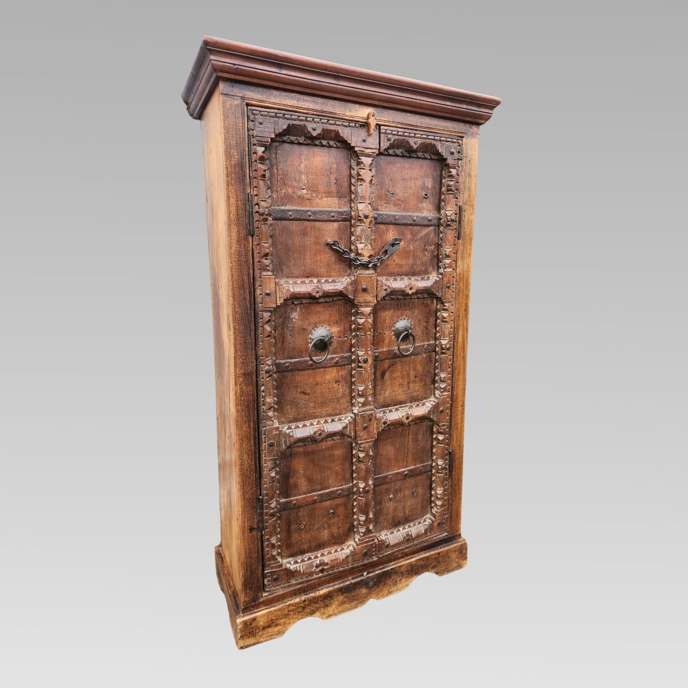 A tall antique Indian cupboard constructed from warm brown reclaimed teak wood with carved frame borders, panelled doors, and rustic iron ring handles. View II