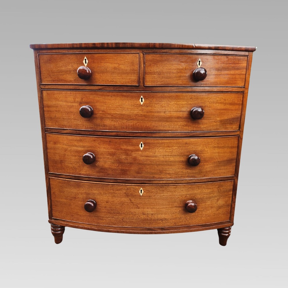 A Victorian mahogany bow-front chest of drawers featuring two short drawers over three long drawers with dark turned handles and turned feet. View II