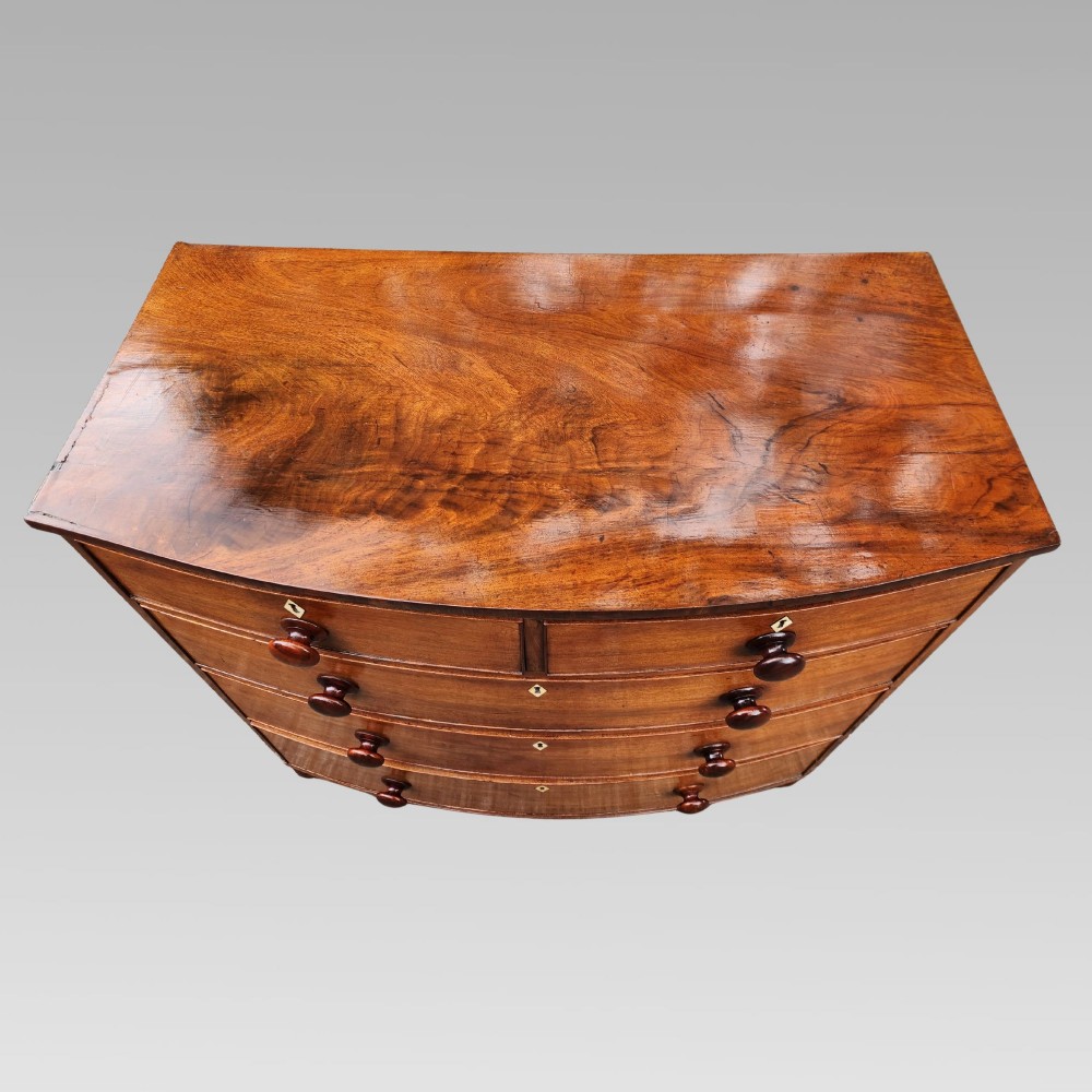 A Victorian mahogany bow-front chest of drawers featuring two short drawers over three long drawers with dark turned handles and turned feet. View III