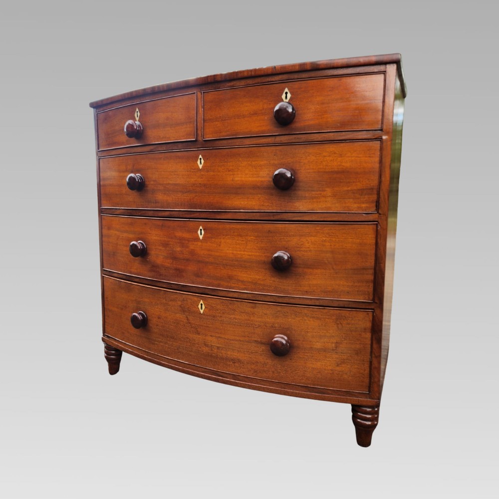 A Victorian mahogany bow-front chest of drawers featuring two short drawers over three long drawers with dark turned handles and turned feet. View IV