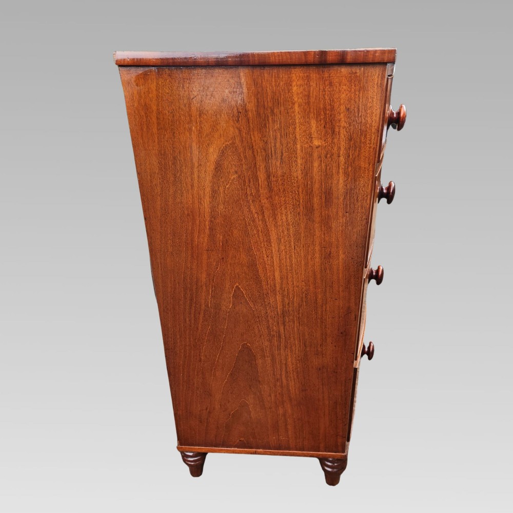 A Victorian mahogany bow-front chest of drawers featuring two short drawers over three long drawers with dark turned handles and turned feet. View V