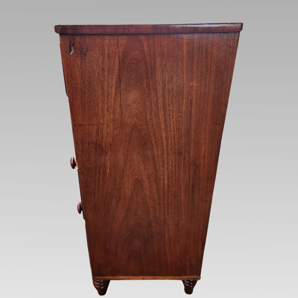 A Victorian mahogany bow-front chest of drawers featuring two short drawers over three long drawers with dark turned handles and turned feet. View VI