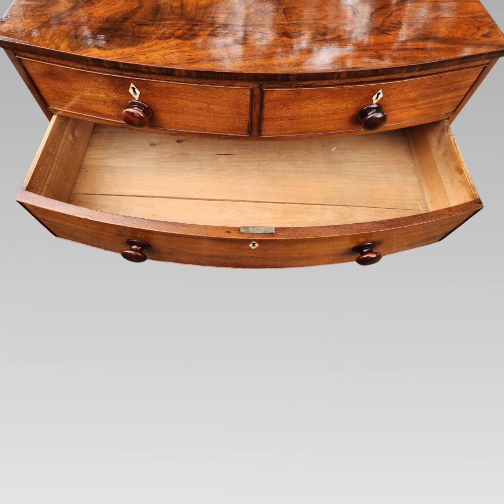 A Victorian mahogany bow-front chest of drawers featuring two short drawers over three long drawers with dark turned handles and turned feet. View IX