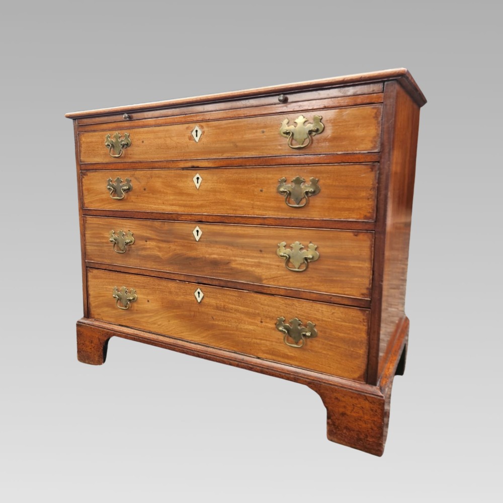 A Georgian mahogany chest of drawers featuring four graduated drawers with brass batwing handles, keyhole escutcheons, a brushing slide, and bracket feet.