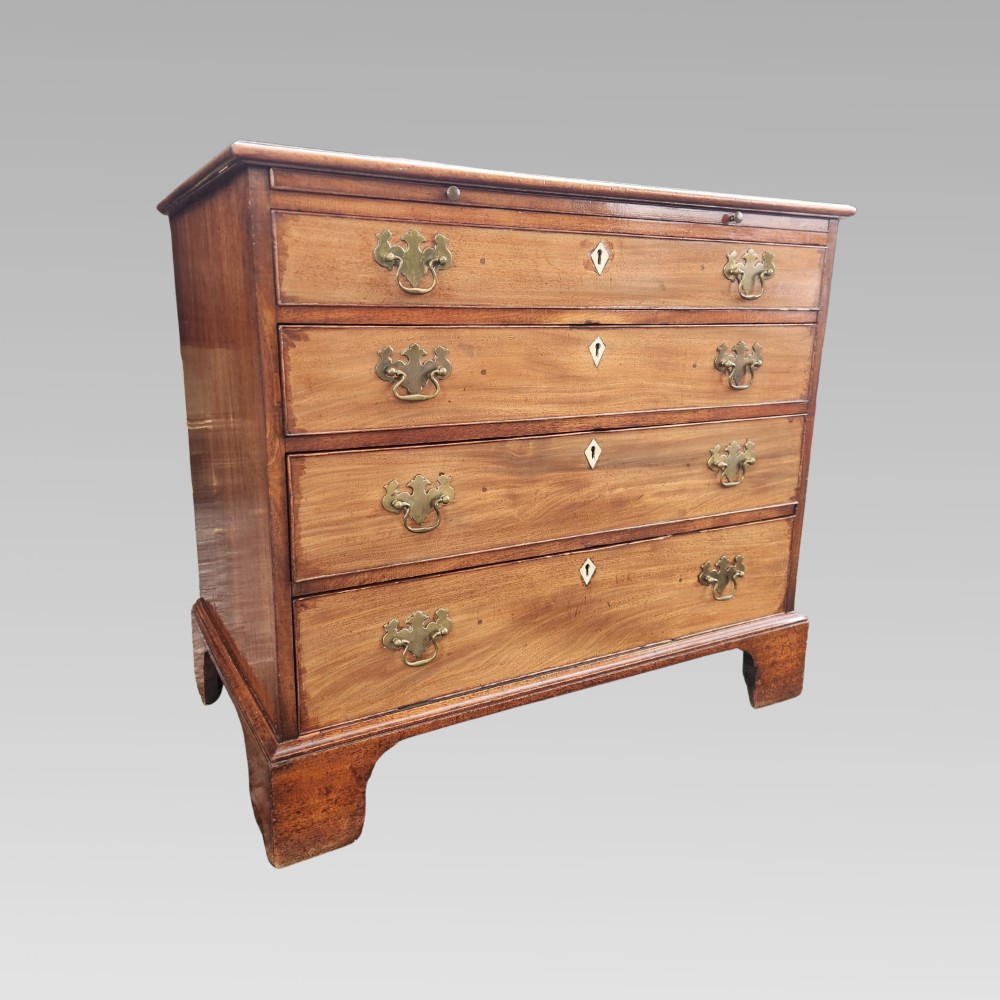 A Georgian mahogany chest of drawers featuring four graduated drawers with brass batwing handles, keyhole escutcheons, a brushing slide, and bracket feet. View III