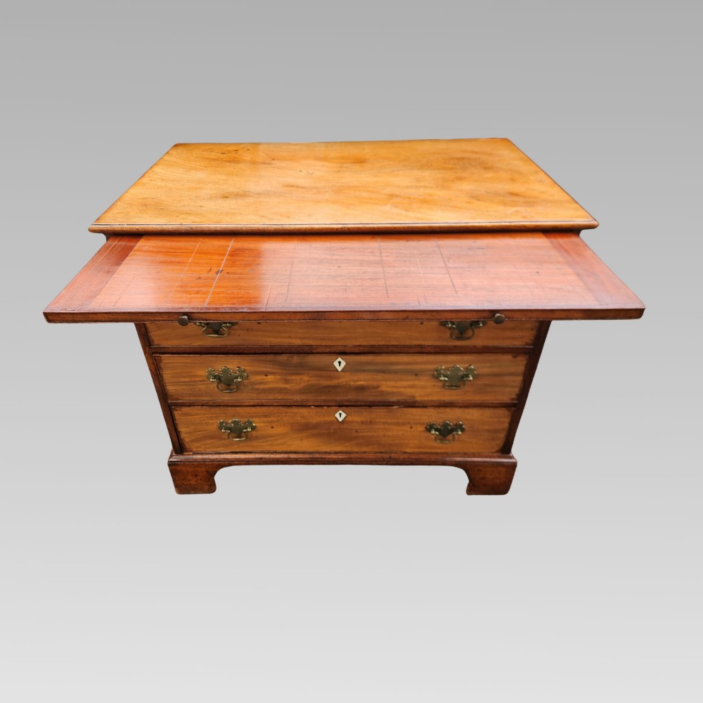 A Georgian mahogany chest of drawers featuring four graduated drawers with brass batwing handles, keyhole escutcheons, a brushing slide, and bracket feet. View IV