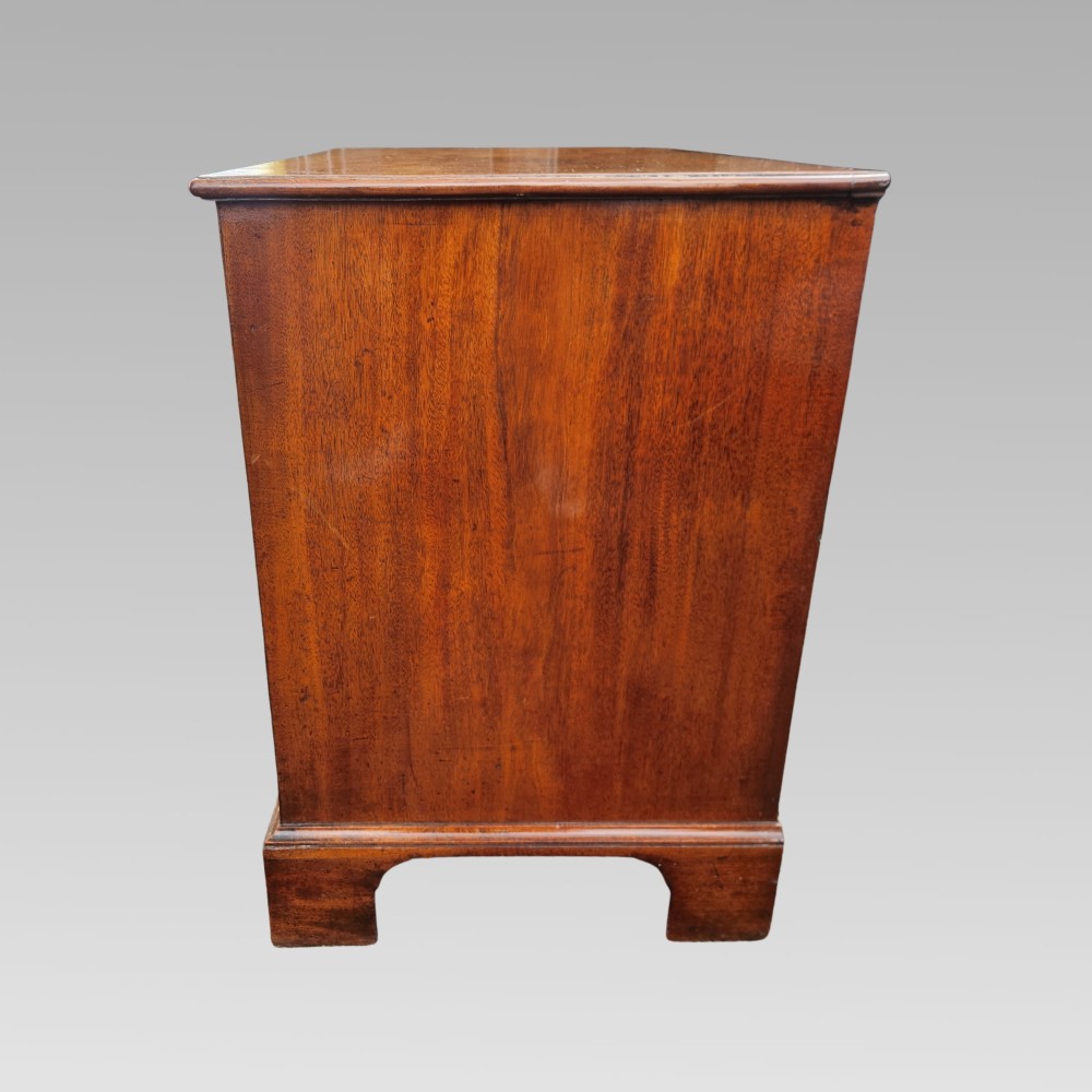 A Georgian mahogany chest of drawers featuring four graduated drawers with brass batwing handles, keyhole escutcheons, a brushing slide, and bracket feet. View VII
